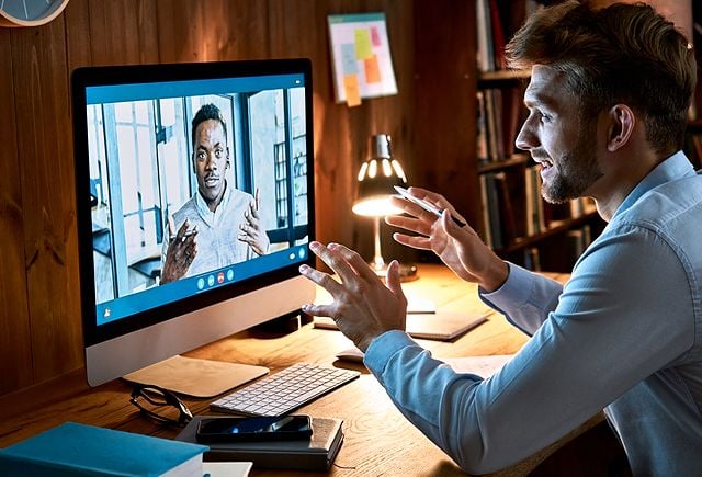 Caucasian business man talking with african male partner coach on video conference call discussing social distance work at virtual remote meeting videoconference chat using pc computer at home office.